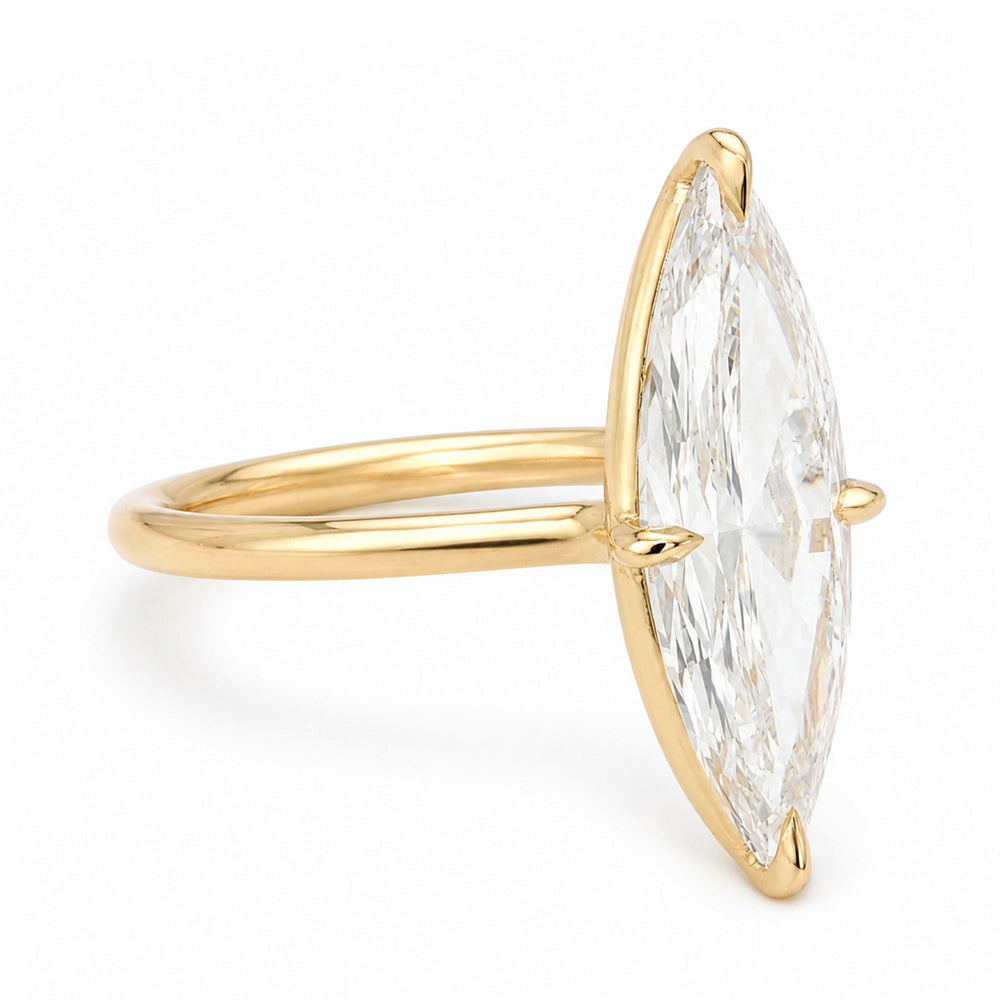 A yellow gold solitaire engagement ring featuring a moval old mine-cut white diamond in a prong setting, shown on a clean white background.