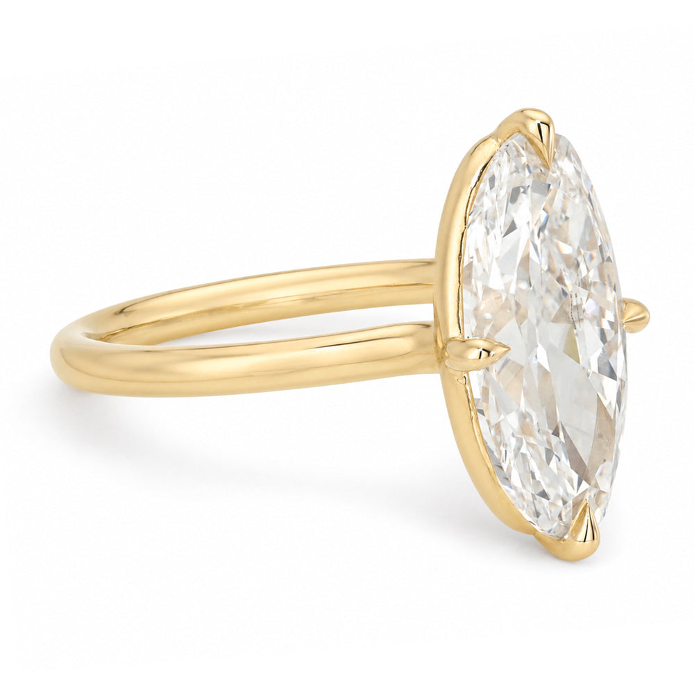 A yellow gold solitaire engagement ring featuring a moval old mine-cut white diamond in a prong setting, shown on a clean white background.