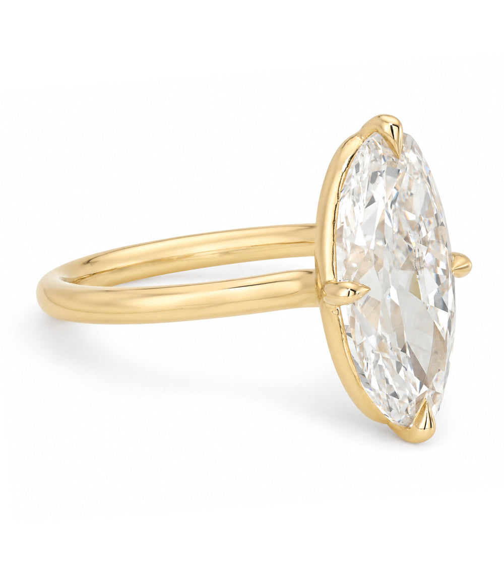 A yellow gold solitaire engagement ring featuring a moval old mine-cut white diamond in a prong setting, shown on a clean white background.