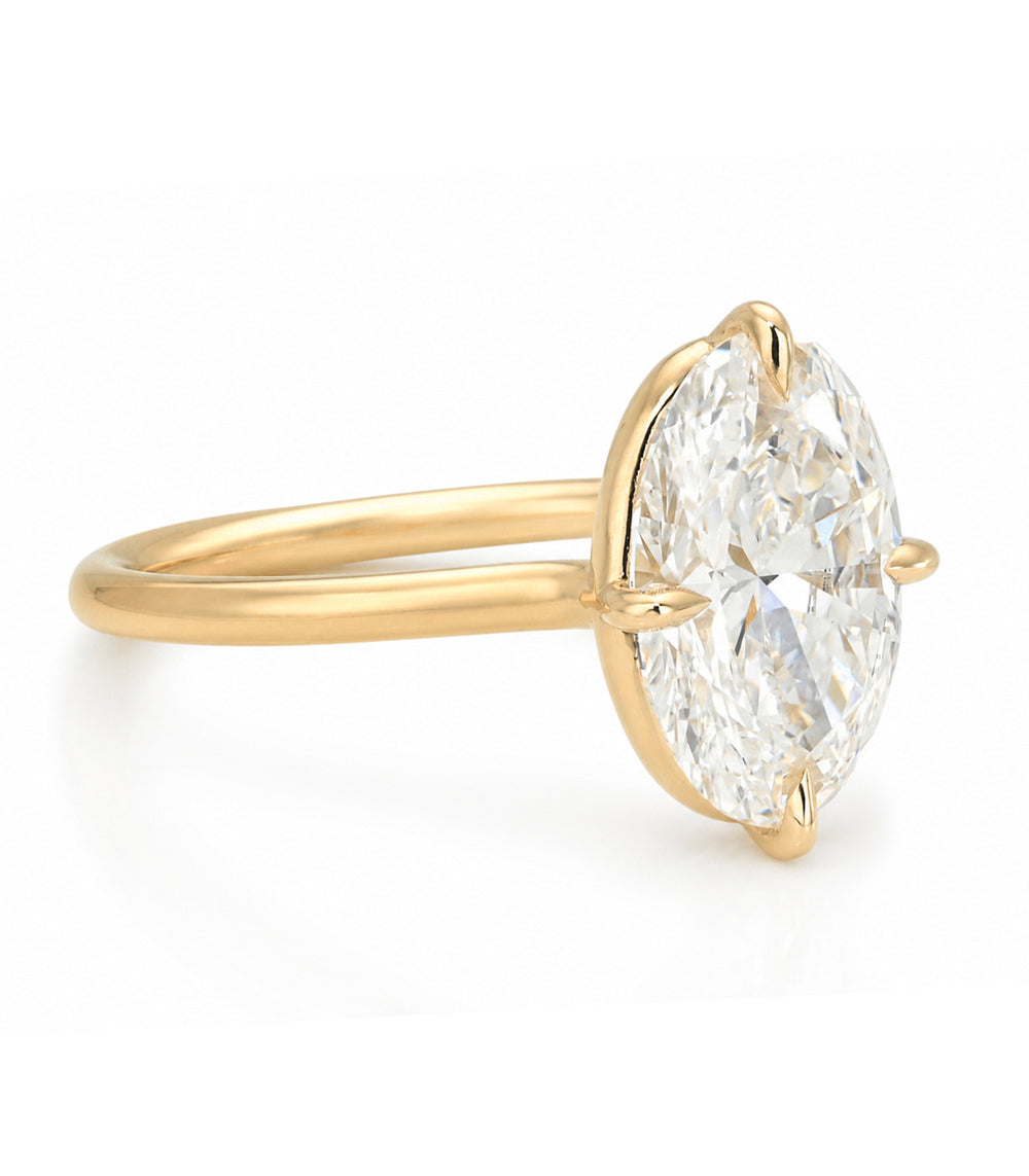 A yellow gold solitaire engagement ring featuring a oval brilliant-cut white diamond in a prong setting, shown on a clean white background.