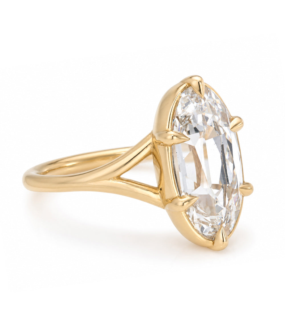 A yellow gold solitaire engagement ring featuring a moval old mine-cut white diamond in a bezel and 6 claw prong split shank setting, shown on a clean white background.