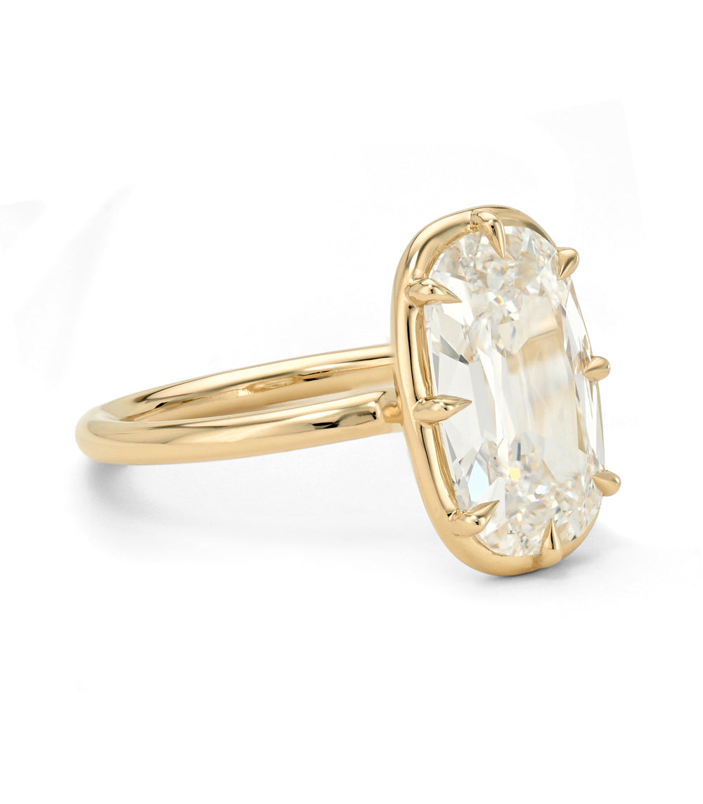 A yellow gold ring featuring a large, cushion-cut clear gemstone in a prong setting, shown on a clean white background.