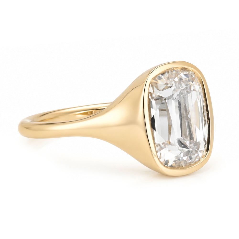A yellow gold solitaire engagement ring featuring a cushion old mine-cut white diamond in a bezel tapered setting, shown on a clean white background.