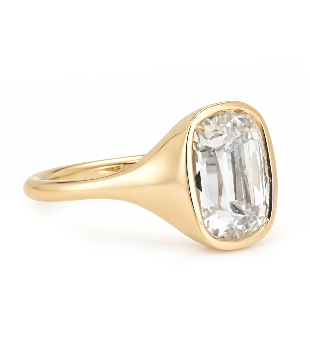 A yellow gold solitaire engagement ring featuring a cushion old mine-cut white diamond in a bezel tapered setting, shown on a clean white background.
