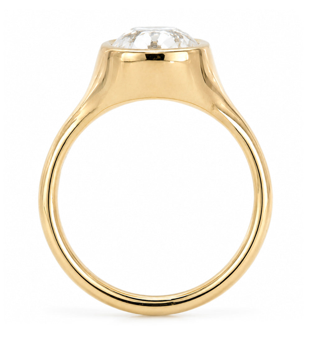 A yellow gold solitaire engagement ring featuring a cushion old mine-cut white diamond in a bezel tapered setting, shown on a clean white background.