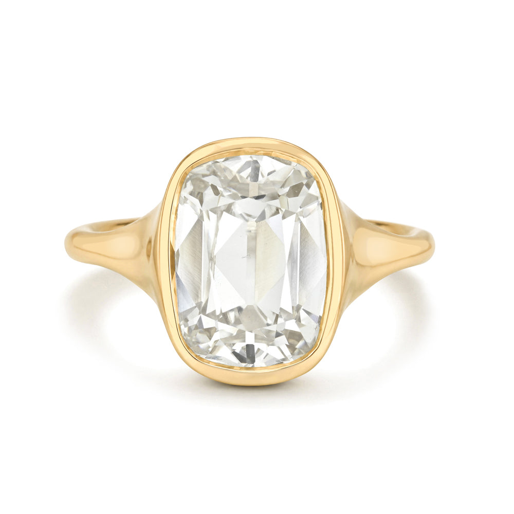 A yellow gold ring featuring a large cushion-cut white diamond in a bezel setting, shown against a plain white background.