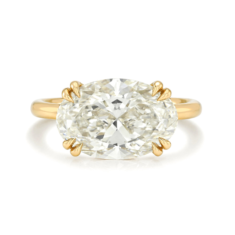 An oval brilliant cut diamond ring with a yellow gold band and double prong setting, photographed on a clean white background.