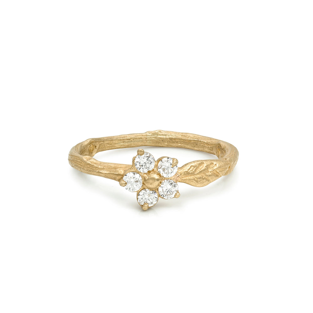A gold ring designed like a flower bud growing from a textured branch, featuring five clear round-cut gemstones, shown on a plain white background.