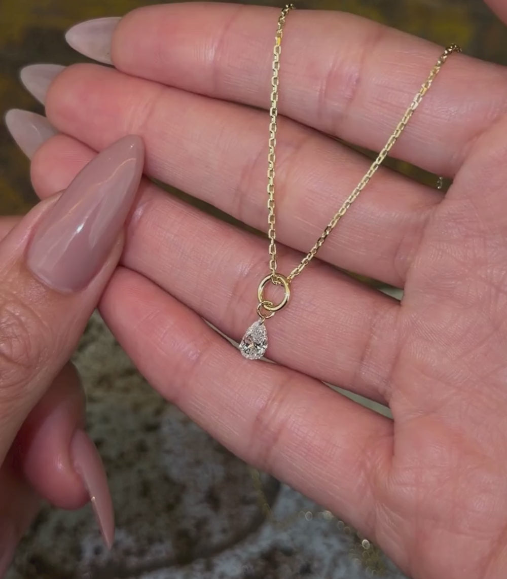 14K yellow gold chain necklace with a pear brilliant cut diamond pendant shown with hands.