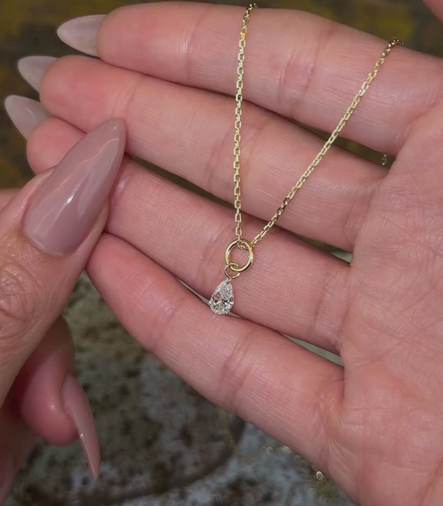 14K yellow gold chain necklace with a pear brilliant cut diamond pendant shown with hands.