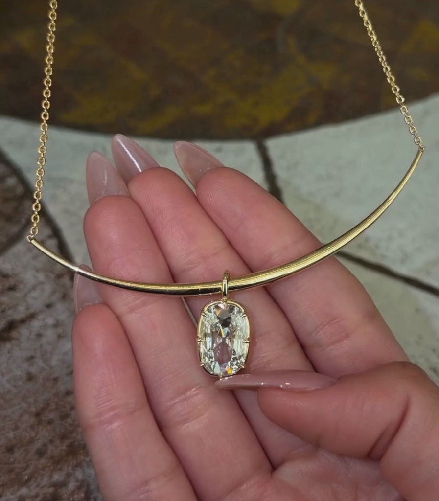 14K yellow gold bar chain necklace with a flat elongated cushion old mine cut diamond pendant shown with hands.