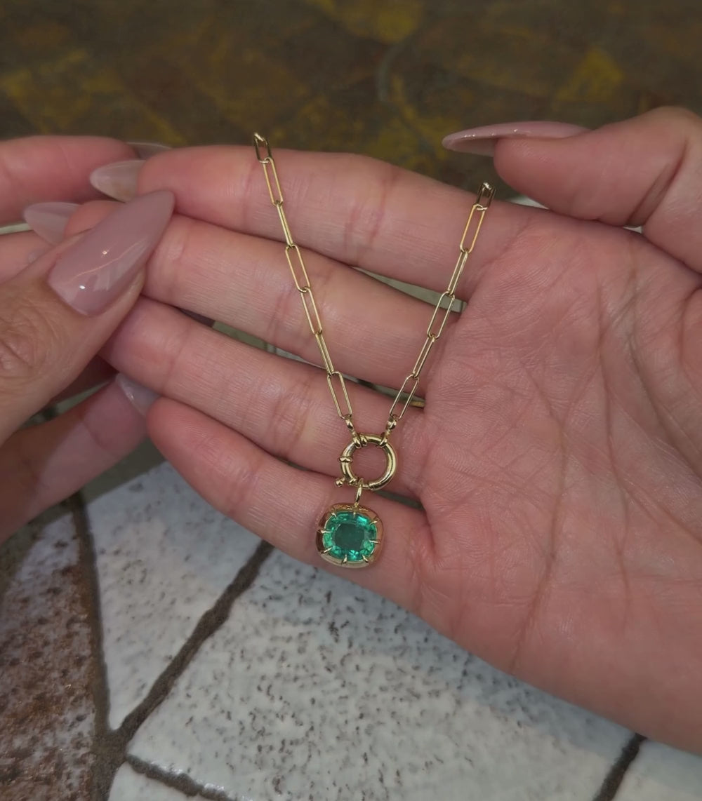 14K yellow gold cable chain necklace with an elongated cushion emerald pendant and spring ring closure shown with hands.