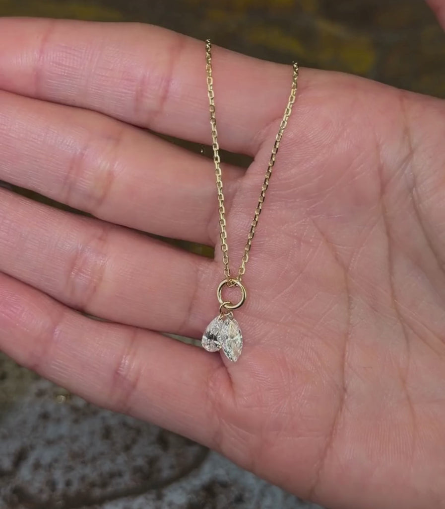 14K yellow gold chain necklace with one pear brilliant cut diamond pendant and one marquise brilliant cut diamond pendant, shown with hands.