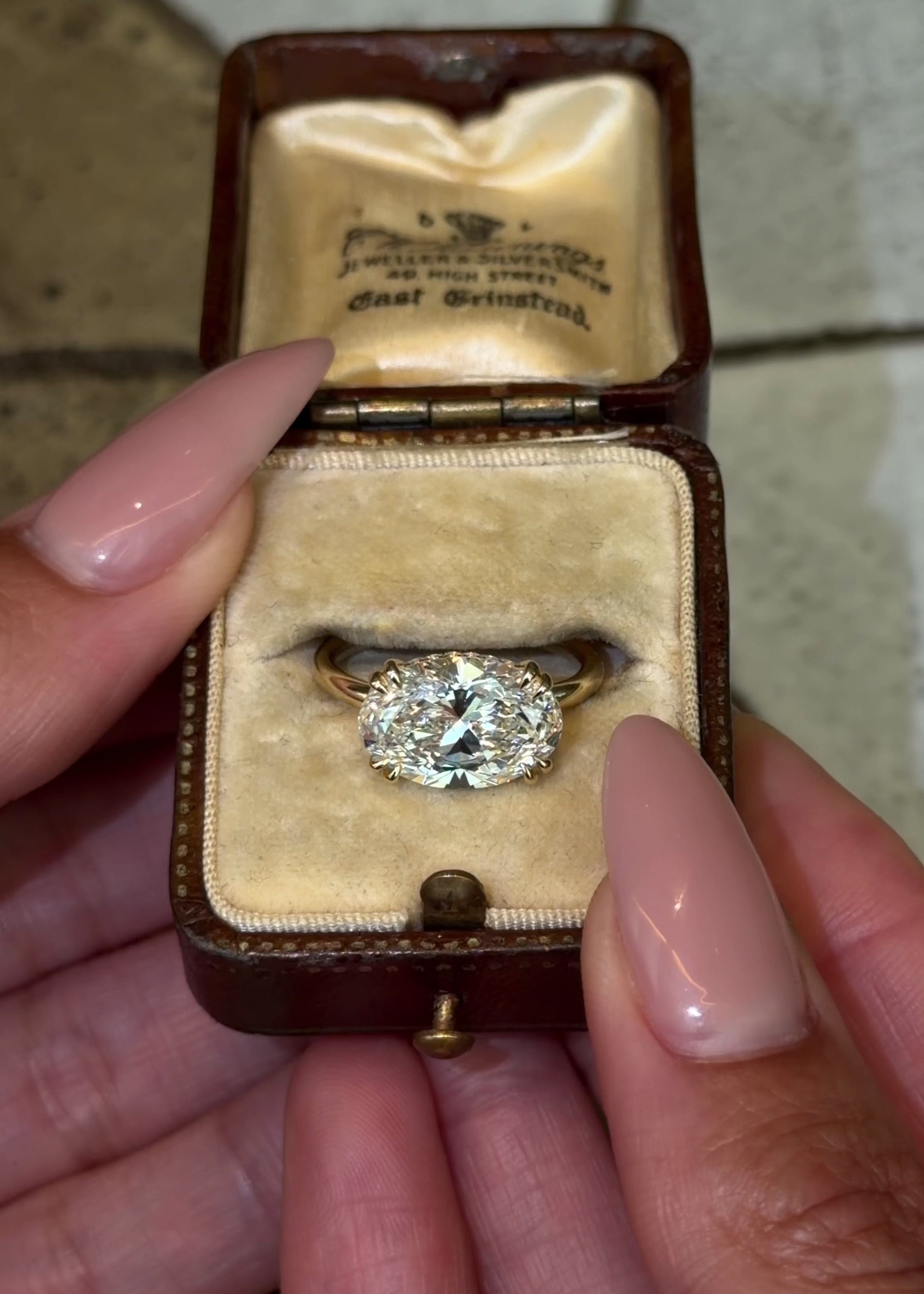 east west oval lab diamond engagement ring with double claw corner prongs and a hidden halo on a thin 14y yellow gold band
