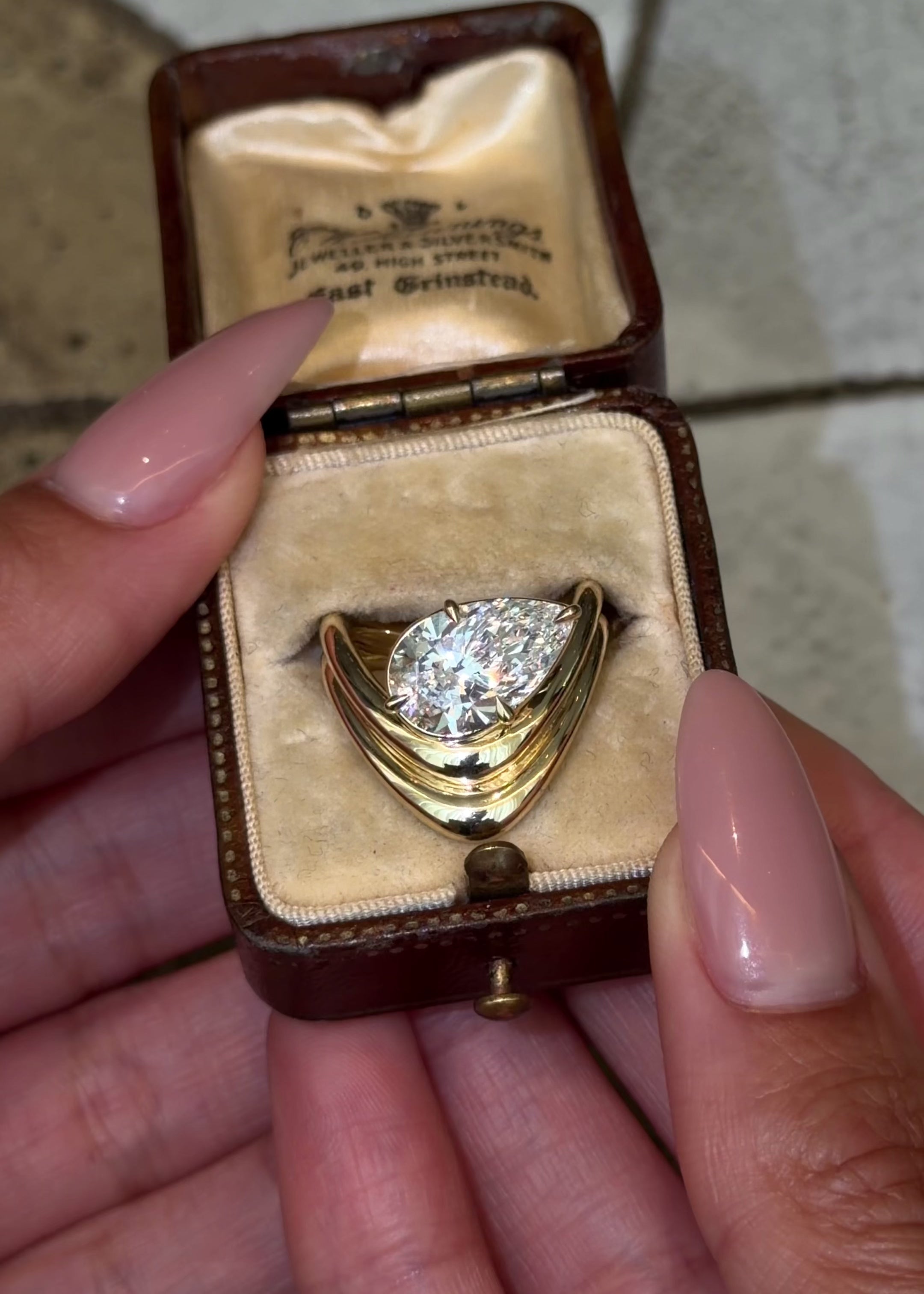 tilted lab diamond pear in a sculptural yellow gold setting featuring two bands of shiny gold