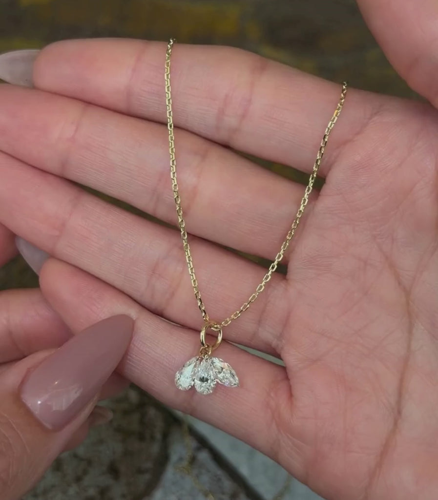 14K yellow gold chain necklace with two pear brilliant cut diamond pendants and one marquise brilliant cut diamond pendant shown with hands.