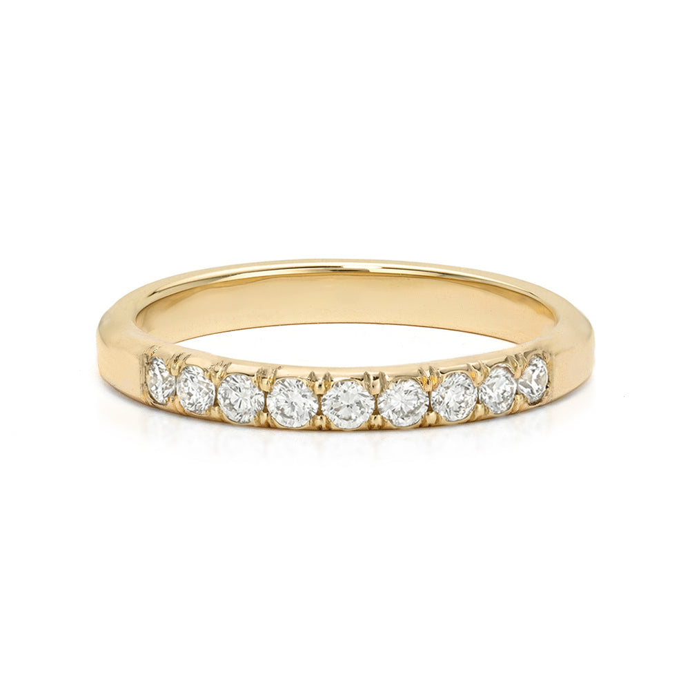 A yellow gold eternity ring featuring a row of round-cut clear diamonds set in a prong setting, shown on a clean white background.