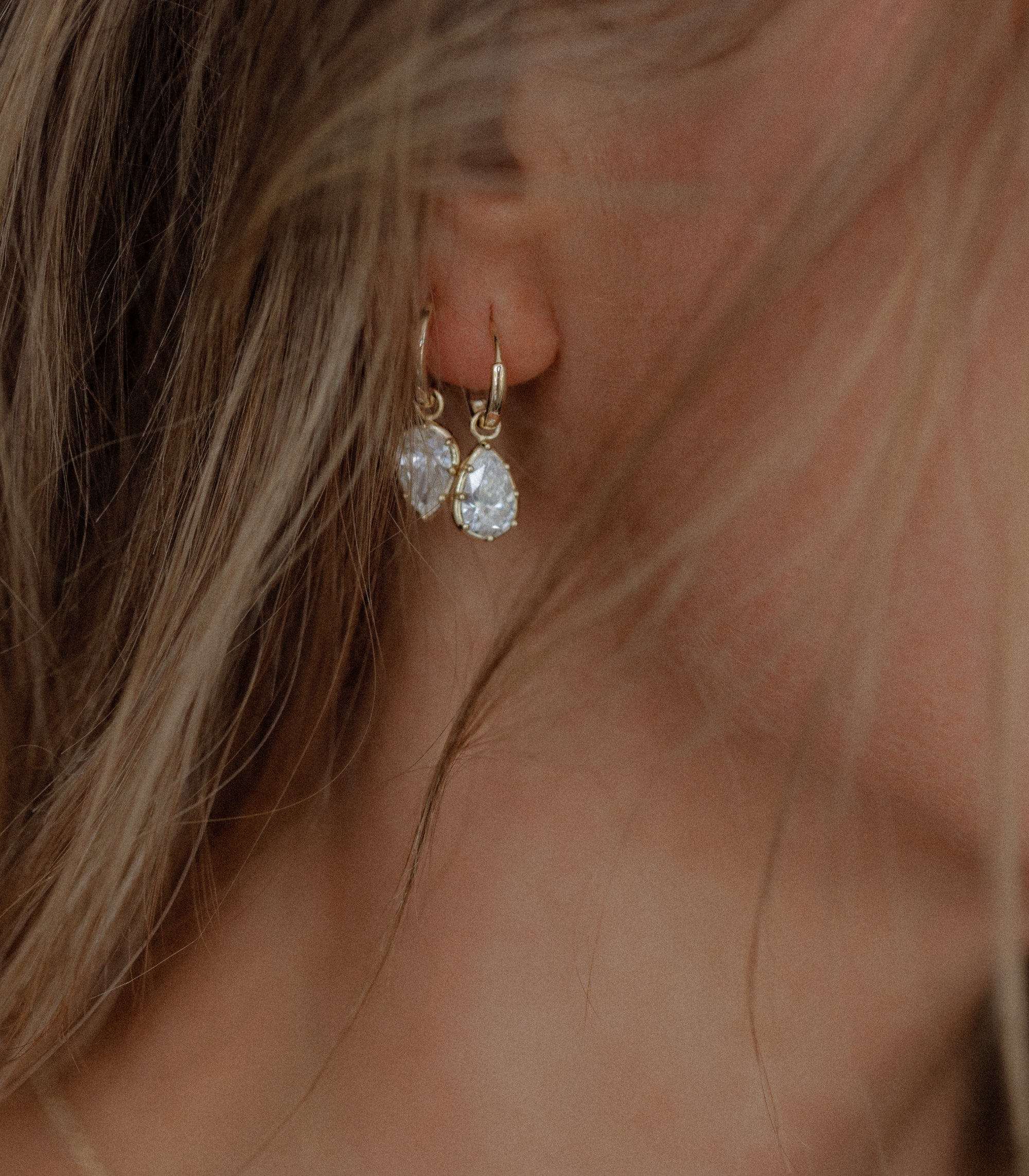 Womans Ear With 14k Yellow Gold Huggie Hoop Earrings With 1ct Diamond Drops