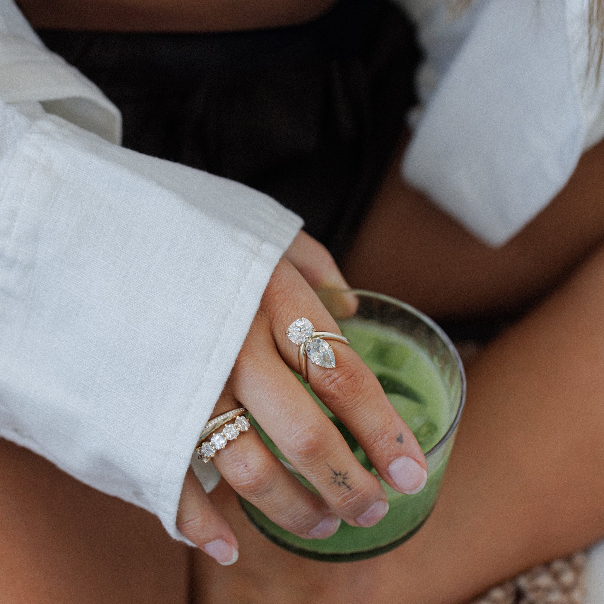 Womans Hand Holding Matcha Latte With Unique Engagement Rings For Contemporary Women Toi Et Moi Designs