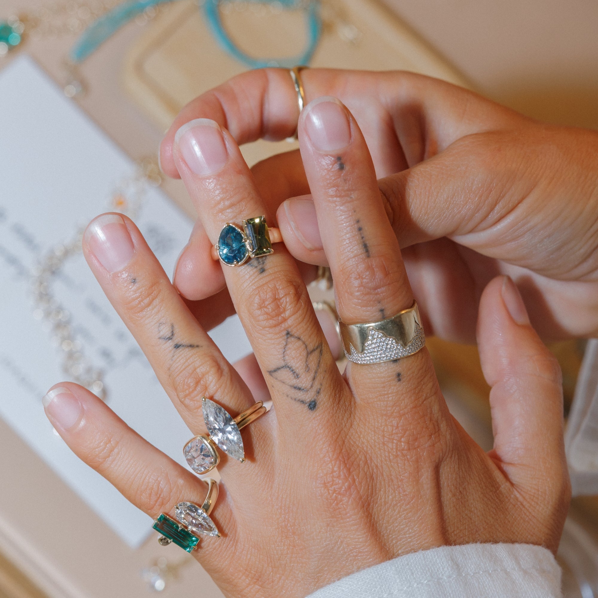 Womans Hands Putting On Stack Of Rings With Sapphire Toi Et Moi Champagne Diamond Solitaire Style Engagement Rings